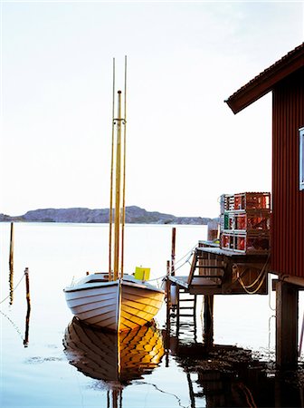 simsearch:6102-07769234,k - Un petit bateau de pêche par une jetée dans le soleil du soir, Suède. Photographie de stock - Premium Libres de Droits, Code: 6102-03828409