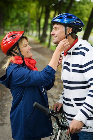 A couple helping each other fastening a cycle helmet, Sweden. Stock Photo - Premium Royalty-Free, Code: 6102-03828510