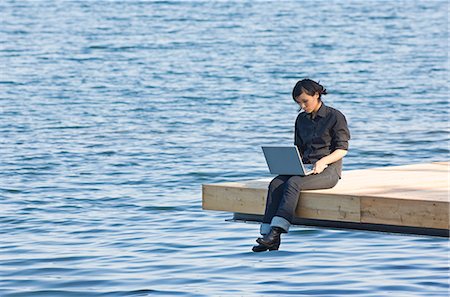 Jeune femme sur une jetée à l'aide d'un ordinateur portable, Suède. Photographie de stock - Premium Libres de Droits, Code: 6102-03828833