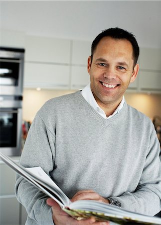simsearch:6102-03905315,k - Un homme souriant, tenant un livre de cuisine, Suède. Photographie de stock - Premium Libres de Droits, Code: 6102-03904059
