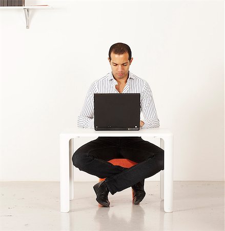 sitting at table white background - Man using a laptop by a miniature table, Sweden. Stock Photo - Premium Royalty-Free, Code: 6102-03904131