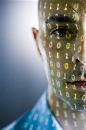 Close-up of a man with digital numbers reflected on his face. Stock Photo - Premium Royalty-Free, Code: 6102-03905397