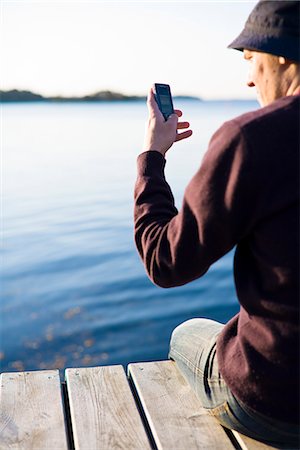 Man on a jetty using a mobile phone, Sweden. Stock Photo - Premium Royalty-Free, Code: 6102-03905648