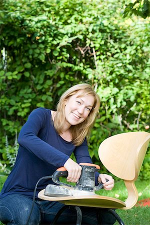 Woman smoothing chair surface Stock Photo - Premium Royalty-Free, Code: 6102-03905844