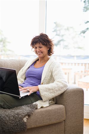 surfing the net - Femme assise sur le canapé et surfer sur internet Photographie de stock - Premium Libres de Droits, Code: 6102-04929458