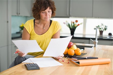paperasserie - Femme assise dans la cuisine avec des factures Photographie de stock - Premium Libres de Droits, Code: 6102-04929476