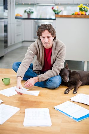 simsearch:6102-04929476,k - Mid-adult man arranging domestic paperwork on floor, while dog is sleeping next to him Fotografie stock - Premium Royalty-Free, Codice: 6102-04929502