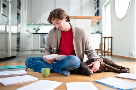 simsearch:6102-04929476,k - Mid-adult man doing paperwork on floor, while dog is sleeping next to him Fotografie stock - Premium Royalty-Free, Codice: 6102-04929518