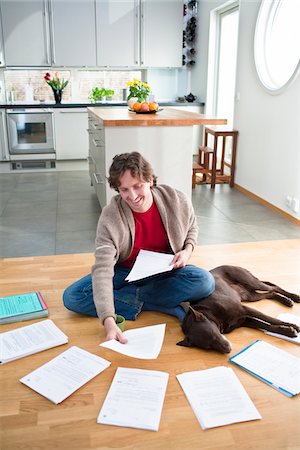 simsearch:6102-04929476,k - Mid-adult man arranging domestic paperwork on floor, while dog is sleeping next to him Fotografie stock - Premium Royalty-Free, Codice: 6102-04929521