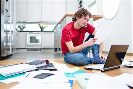 Mid- adult man struggling with domestic paperwork Foto de stock - Sin royalties Premium, Código: 6102-04929522