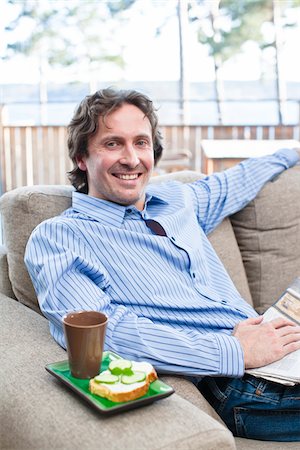 Portrait of cheerful mid-adult man sitting on sofa Stock Photo - Premium Royalty-Free, Code: 6102-04929526