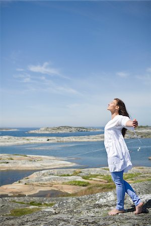 extending - Woman standing on rock with arms up Stock Photo - Premium Royalty-Free, Code: 6102-04929638