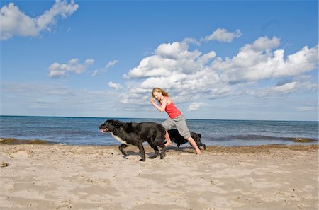 Girl with dogs running on beach Stock Photo - Premium Royalty-Free, Code: 6102-04929783