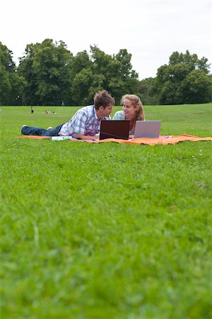 Mid adult couple lying on lawn in park and using laptops Stock Photo - Premium Royalty-Free, Code: 6102-04929882