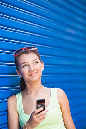 simsearch:6102-04929804,k - Girl in front of blue wall, holding cell phone Stock Photo - Premium Royalty-Free, Code: 6102-04929810