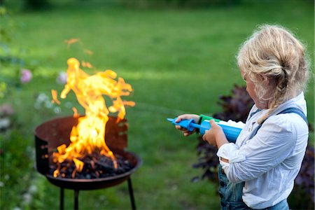 feuer - Fille soufflant le feu dans la grille du barbecue Photographie de stock - Premium Libres de Droits, Code: 6102-05802600