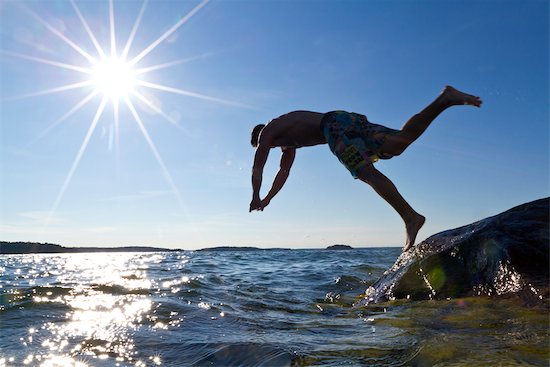 Young man jumping into water Stock Photo - Premium Royalty-Free, Image code: 6102-05955874