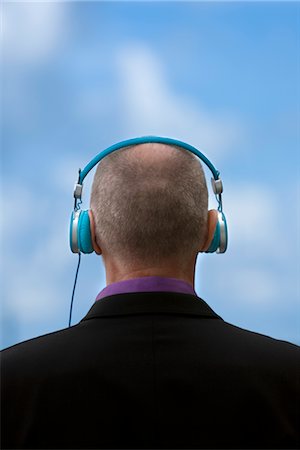 Businessman listening to headphones outdoors Stock Photo - Premium Royalty-Free, Code: 6102-05955885