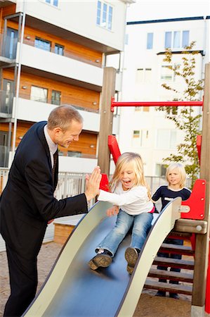 escorregar - Father and daughters playing on slide Foto de stock - Royalty Free Premium, Número: 6102-06025759