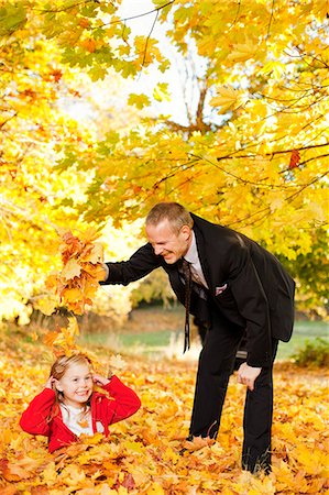 Father and daughter playing with autumn leaves in park Stock Photo - Premium Royalty-Free, Code: 6102-06025776