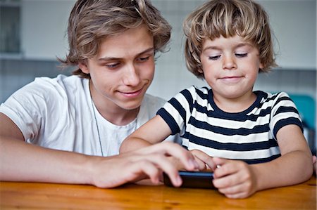 Brothers playing with cell phone Stock Photo - Premium Royalty-Free, Code: 6102-06025841