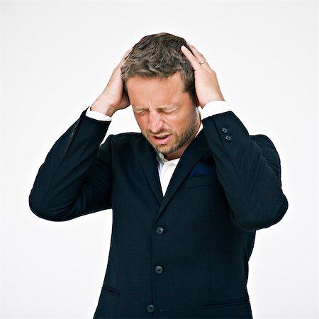 Studio portrait of businessman with head in hands Stock Photo - Premium Royalty-Free, Code: 6102-06025850