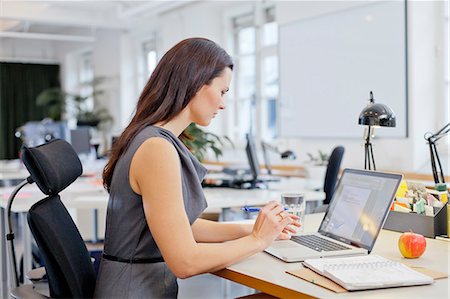 portrait woman focused - Businesswoman using laptop in office Stock Photo - Premium Royalty-Free, Code: 6102-06026054