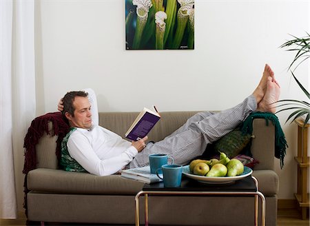 simsearch:693-03307594,k - Mid adult man lying on sofa and reading book Stock Photo - Premium Royalty-Free, Code: 6102-06026022