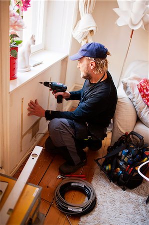 Man drilling in living room Stock Photo - Premium Royalty-Free, Code: 6102-06374537