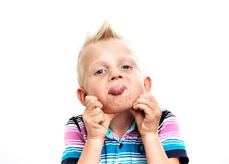 Portrait of boy sticking out tongue, studio shot Stock Photo - Premium Royalty-Free, Code: 6102-06336544