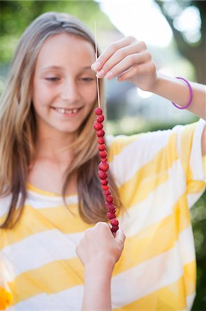 simsearch:6102-08168957,k - Smiling girl holding wild strawberries on string Stock Photo - Premium Royalty-Free, Code: 6102-06336554