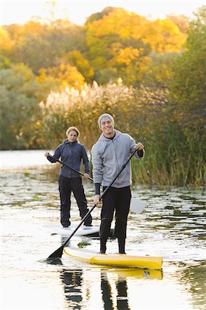 standing - Two people smiling on paddle boards on river Stock Photo - Premium Royalty-Free, Code: 6102-06336949