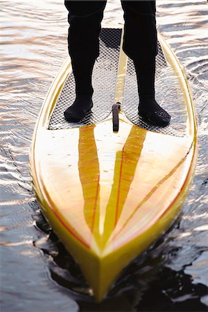 simsearch:6102-06336949,k - Man standing on paddle board in water, low section Fotografie stock - Premium Royalty-Free, Codice: 6102-06336932