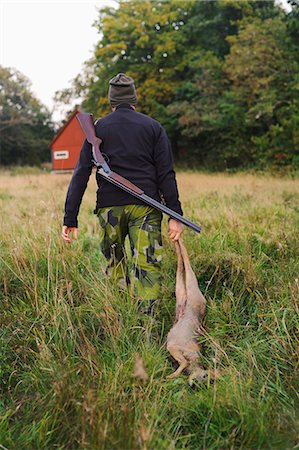 simsearch:640-08089734,k - Hunter dragging deer through field Foto de stock - Royalty Free Premium, Número: 6102-06337050