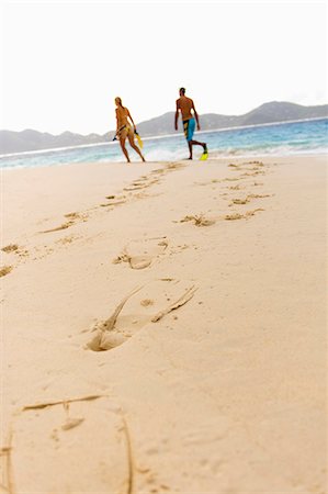 footprints - Diving flipper prints on sand, mid adult couple in background Stock Photo - Premium Royalty-Free, Code: 6102-06337135