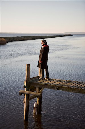 A senior woman standing on a jetty by the sea, Sweden. Stock Photo - Premium Royalty-Free, Code: 6102-06470393