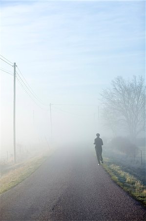 simsearch:6102-06470793,k - One person running on a hazy road, Sweden. Photographie de stock - Premium Libres de Droits, Code: 6102-06470797