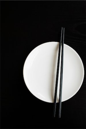 palillo (oriental) - White plate with chopsticks on black background Foto de stock - Sin royalties Premium, Código: 6102-06471006