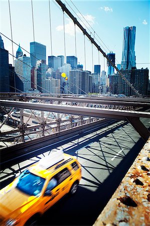 simsearch:6102-07768730,k - Yellow taxi on Brooklyn Bridge with skyscrapers in background Foto de stock - Sin royalties Premium, Código: 6102-06471243