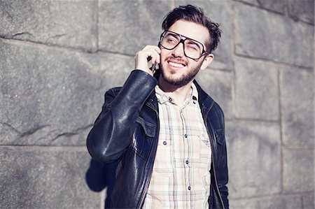 eyeglasses outdoor - Smiling young man talking via cell phone Stock Photo - Premium Royalty-Free, Code: 6102-06471250