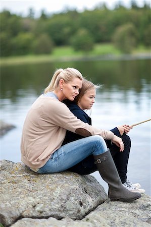 Rear view of young couple in waders sea fishing stock photo