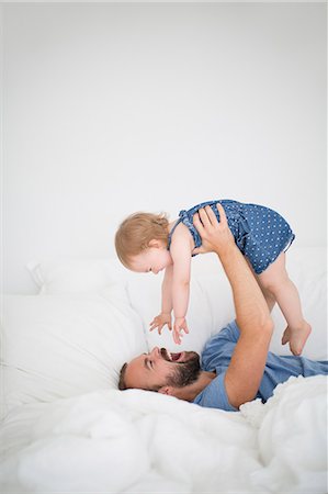 positive - Man lying on bed and holding little daughter Stock Photo - Premium Royalty-Free, Code: 6102-06777445