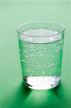 drinking glass studio shot - Glass of sparkling water on green background Stock Photo - Premium Royalty-Free, Code: 6102-06777576