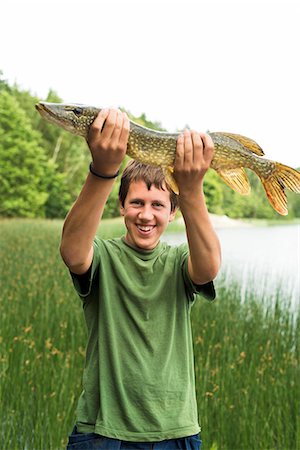 Smiling teenage boy with caught fish Photographie de stock - Premium Libres de Droits, Code: 6102-07158165