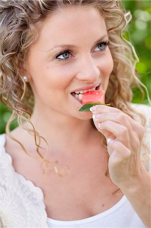 simsearch:6102-07282630,k - Smiling woman eating watermelon at garden party Photographie de stock - Premium Libres de Droits, Code: 6102-07282627