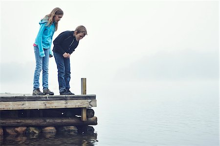 scandinavia lake friends - Boy and girl on jetty looking at water, Okno, Smiland, Sweden Stock Photo - Premium Royalty-Free, Code: 6102-07602568