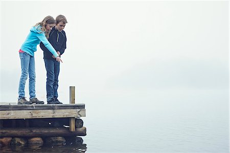 people pointing at a girl - Boy and girl on jetty looking at water, Okno, Smiland, Sweden Stock Photo - Premium Royalty-Free, Code: 6102-07602569