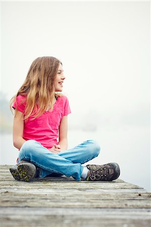 sitting cross legged - Girl sitting on jetty, Okno, Smiland, Sweden Stock Photo - Premium Royalty-Free, Code: 6102-07602573