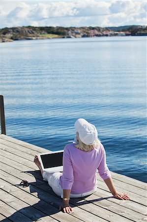 relaxing on dock - Senior woman sitting on jetty, Bohuslan, Sweden Stock Photo - Premium Royalty-Free, Code: 6102-07602706