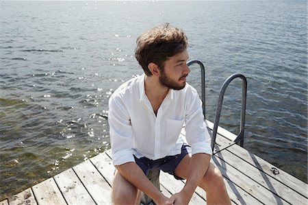 Young man sitting on jetty, Sweden Stock Photo - Premium Royalty-Free, Code: 6102-07602822
